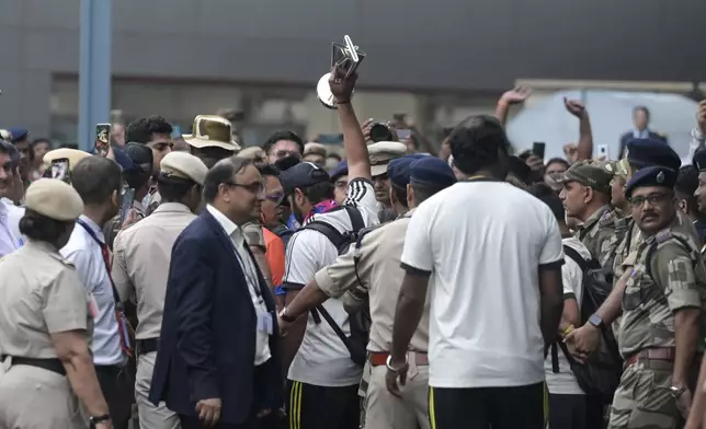 India's captain Rohit Sharma is surrounded by officials as he lifts the winners' trophy after arriving at the Indira Gandhi International Airport in New Delhi, India, Thursday, July 4, 2024. Indian cricket team returned Thursday after winning the T20 Cricket World Cup hosted by the United States and the West Indies. (AP Photo)