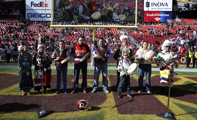 FILE - Members of the Blackfeet Nation perform as part of the Washington football team's observance of Native American Heritage Month prior to an NFL football game on Nov. 24, 2019, in Landover, Md. Many Native Americans thought a bitter debate over the U.S. capital’s football mascot was over when the team became the Washington Commanders. The original logo was designed by a member of the Blackfeet Nation. Now a white Republican U.S. senator from Montana is reviving the debate by blocking a bill funding the revitalization of the team's stadium unless the NFL and the Commanders bring back the former logo in some form. (AP Photo/Alex Brandon, File)