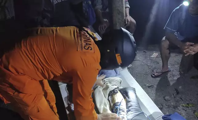 In this photo released by the Indonesian National Search and Rescue Agency (BASARNAS), an injured victim of a landslide is attended to in Suwawa on Sulawesi Island, Indonesia, early Monday, July 8, 2024. The landslide triggered by torrential rains crashed onto an unauthorized gold mining operation on Indonesia's Sulawesi island, killing a number of miners, officials said Monday. (BASARNAS via AP)