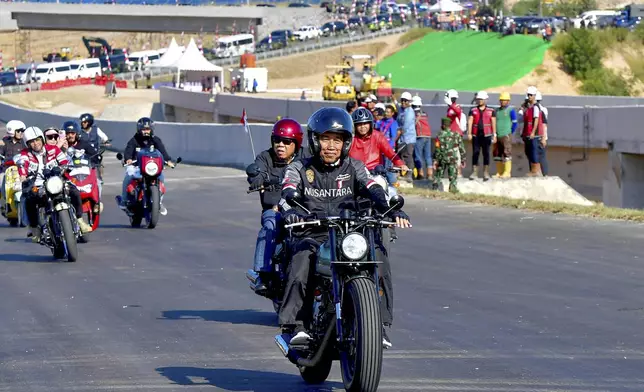 In this photo released by Indonesian Presidential Palace, Indonesian President Joko Widodo, center, rides a motorcycle in the new capital city Nusantara in Penajam Paser Utara, East Kalimantan, Indonesia, Sunday, July 28, 2024. Widodo started work Monday from the new presidential palace in his country's ambitious new capital Nusantara, where he intends to spend the last few months of his presidency. (Rusman/Indonesian President Palace via AP)