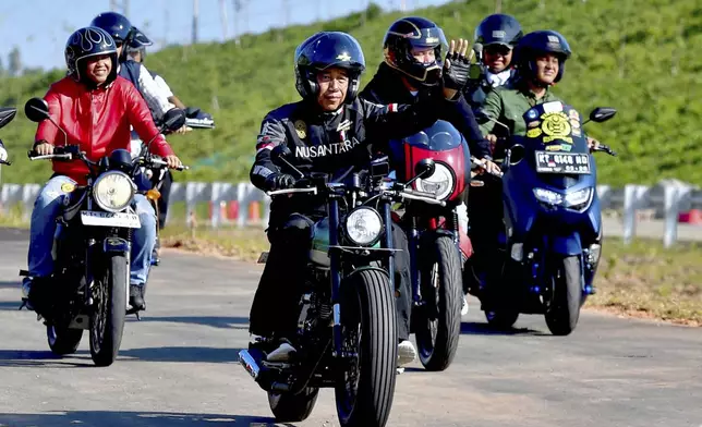 In this photo released by Indonesian Presidential Palace, Indonesian President Joko Widodo, center, rides a motorcycle in the new capital city Nusantara in Penajam Paser Utara, East Kalimantan, Indonesia, Sunday, July 28, 2024. Widodo started work Monday from the new presidential palace in his country's ambitious new capital Nusantara, where he intends to spend the last few months of his presidency. (Rusman/Indonesian President Palace via AP)