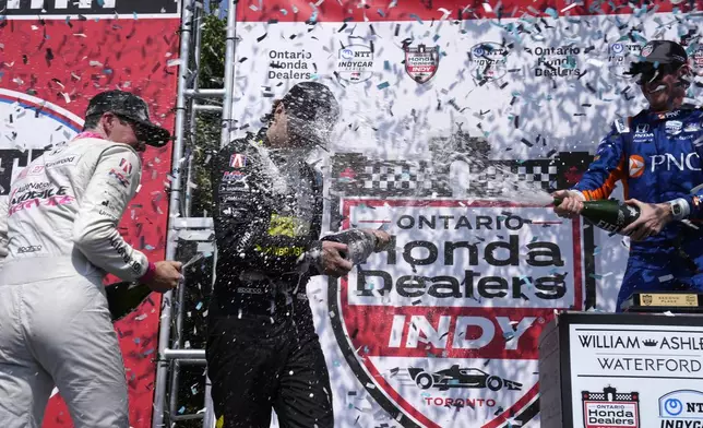 Winner Colton Herta, center, of the United States, second-place Kyle Kirkwood, left, also of the United States, and third-place Scott Dixon, right, of New Zealand, celebrate on the podium after an IndyCar auto race in Toronto, Sunday, July 21, 2024. (Frank Gunn/The Canadian Press via AP)