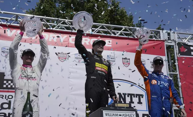 Winner Colton Herta, center, of the United States, second-place Kyle Kirkwood, left, also of the United States, and third-place Scott Dixon, right, of New Zealand, celebrate on the podium after an IndyCar auto race in Toronto, Sunday, July 21, 2024. (Frank Gunn/The Canadian Press via AP)