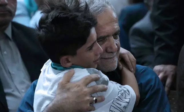 Iran's President-elect Masoud Pezeshkian hugs a boy in a meeting a day after the presidential election, at the shrine of the late revolutionary founder Ayatollah Khomeini, just outside Tehran, Iran, Saturday, July 6, 2024. (AP Photo/Vahid Salemi)