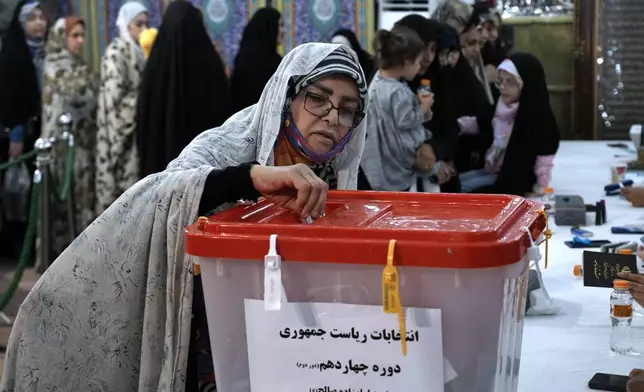 A woman casts her vote for the presidential election in a polling station at the shrine of Saint Saleh in northern Tehran, Iran, Friday, July 5, 2024. Iran held a runoff presidential election on Friday that pitted a hard-line former nuclear negotiator against a reformist lawmaker. (AP Photo/Vahid Salemi)