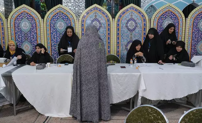 A woman gets her ballot to vote for the presidential election in a polling station at the shrine of Saint Saleh in northern Tehran, Iran, early Saturday, July 6, 2024. Iran held a runoff presidential election on Friday that pitted a hard-line former nuclear negotiator against a reformist lawmaker. (AP Photo/Vahid Salemi)