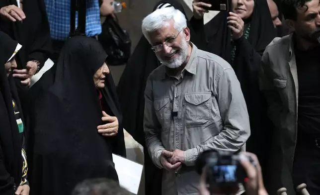 Iranian presidential candidate Saeed Jalili, right, a hard-line former nuclear negotiator, listens to a woman during a campaign stop at a sports hall in Tehran, Iran, Sunday, June 30, 2024. (AP Photo/Vahid Salemi)