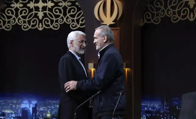 In this photo made available by Iranian state-run TV, IRIB, Iranian presidential candidate Saeed Jalili, left, a hard-line former nuclear negotiator, and reformist candidate Masoud Pezeshkian greet one another at the conclusion of a debate at the TV studio in Tehran, Iran, Monday, June 1, 2024. (Morteza Fakhri Nezhad/IRIB via AP)
