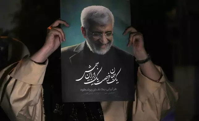 A supporter of Iranian presidential candidate Saeed Jalili holds up a poster of Jalili during his campaign stop in Tehran, Iran, Wednesday, June 26, 2024. (AP Photo/Vahid Salemi)