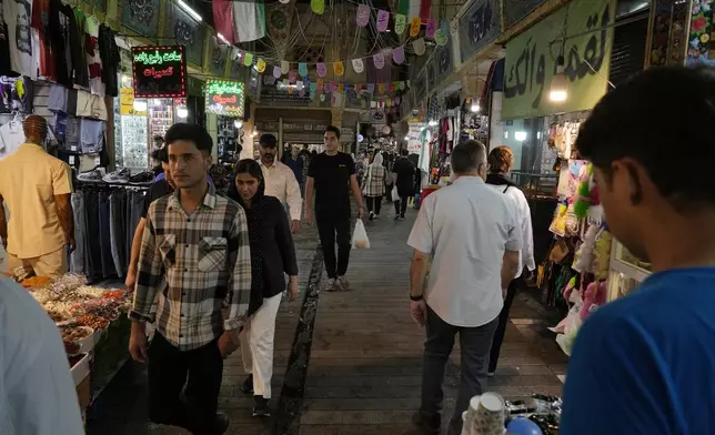 People walk through the Tajrish traditional bazaar in northern Tehran, Iran, Tuesday, July 2, 2024. Comments suggesting that Iran's reformist presidential candidate could increase government-set gasoline prices have raised fears of a repeat of nationwide protests. (AP Photo/Vahid Salemi)