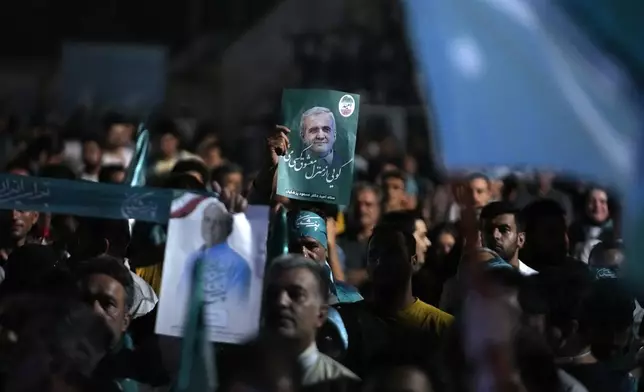 Supporters of the reformist candidate for the Iran's presidential election Masoud Pezeshkian hold up his posters during a campaign rally in Tehran, Iran, Wednesday, July 3, 2024. Comments suggesting that Iran's reformist presidential candidate could increase government-set gasoline prices have raised fears of a repeat of nationwide protests. (AP Photo/Vahid Salemi)