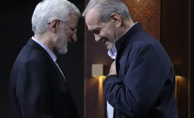In this picture made available by Iranian state-run TV, IRIB, candidate for the presidential election Saeed Jalili, left, a hard-line former Iranian top nuclear negotiator, and reformist candidate Masoud Pezeshkian shake hands after the conclusion their debate at the TV studio in Tehran, Iran, Monday, July 1, 2024. (Morteza Fakhri Nezhad/IRIB via AP)