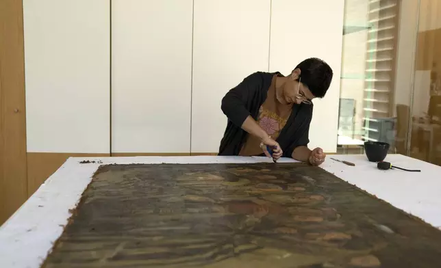 Sarah Reichert restores a painting in a conservation lab during the inauguration of The Moshal Shoah Legacy Campus and The David and Fela Shapell Family Collections Center, at Yad Vashem World Holocaust Remembrance Center in Jerusalem, Monday, July 8, 2024. Israel's national Holocaust museum opened a new conservation facility in Jerusalem, which will preserve, restore, and store the more than 45,000 artifacts and works of art in a vast new building, including five floors of underground storage. (AP Photo/Maya Alleruzzo)