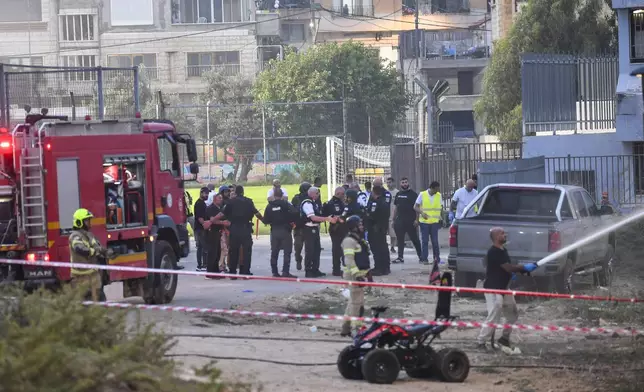 Israeli police officers and firefighters work at the site of a rocket attack in Majdal Shams, in the Israeli-controlled Golan Heights, Saturday, July 27, 2024. (AP Photo/Gil Eliyahu)