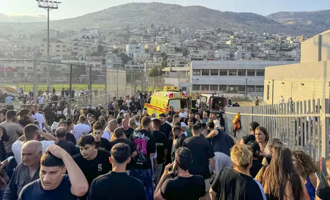 Residence and paramedics rush to help children moments after a rocket attack hit a soccer field in the Druze town of Majdal Shams in the Israeli-controlled Golan of Heights, Saturday, July 27, 2024. (AP Photo/Hassan Shams)