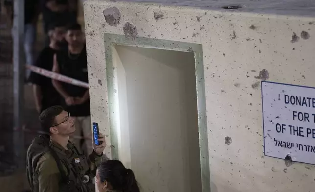 Israeli soldiers check a shelter damaged from shrapnel at a soccer field that was hit by a rocket, killing multiple children and teenagers, in the Druze town of Majdal Shams, in the Israeli-annexed Golan Heights, Saturday, July 27, 2024. (AP Photo/Leo Correa)