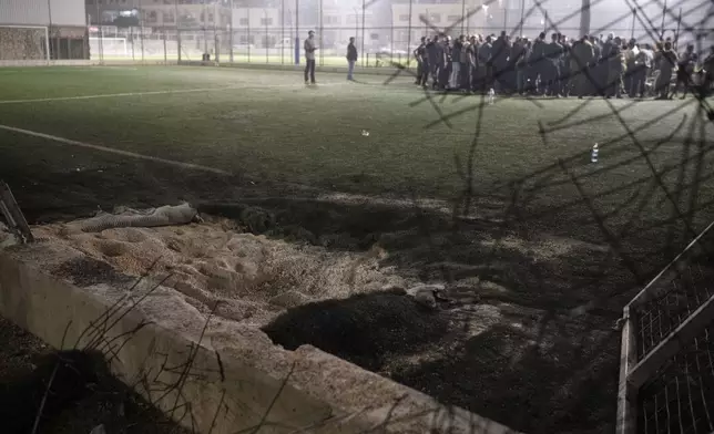 Residents gather with authorities at a soccer field that was hit by a rocket, killing multiple children and teenagers, in the Druze town of Majdal Shams, in the Israeli-annexed Golan Heights, Saturday, July 27, 2024. (AP Photo/Leo Correa)