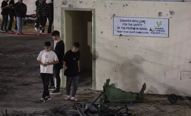 Youth walk next to a shelter damaged from shrapnel at a soccer field that was hit by a rocket, killing multiple children and teenagers, in the Druze town of Majdal Shams, in the Israeli-annexed Golan Heights, Saturday, July 27, 2024. (AP Photo/Leo Correa)