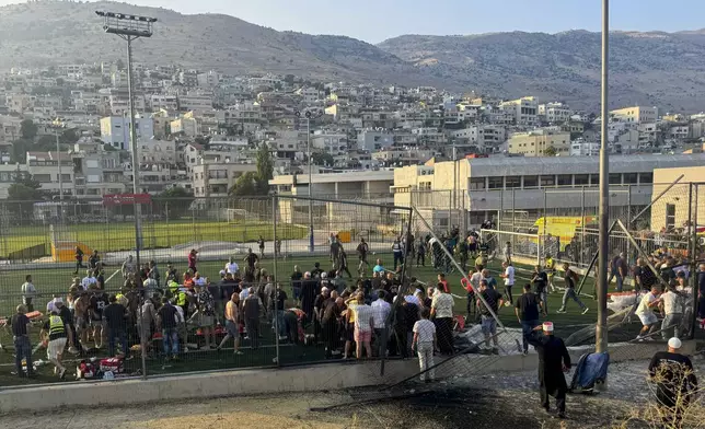 Residence and paramedics rush to help children moments after a rocket attack hit a soccer field in the Druze town of Majdal Shams in the Israeli-controlled Golan of Heights, Saturday, July 27, 2024. (AP Photo/Hassan Shams)