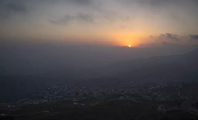 The sun sets behind the mountains next to the the towns of Kiryat Shmona and Metula, located near the border with Lebanon, as seen from Mas'ade, a village in the Israeli-controlled Golan Heights, Sunday, June 23, 2024. (AP Photo/Leo Correa)