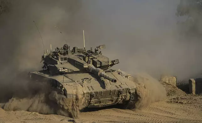 An Israeli soldier moves on the top of a tank near the Israeli-Gaza border, as seen from southern Israel, Sunday, July 14, 2024. (AP Photo/Tsafrir Abayov)