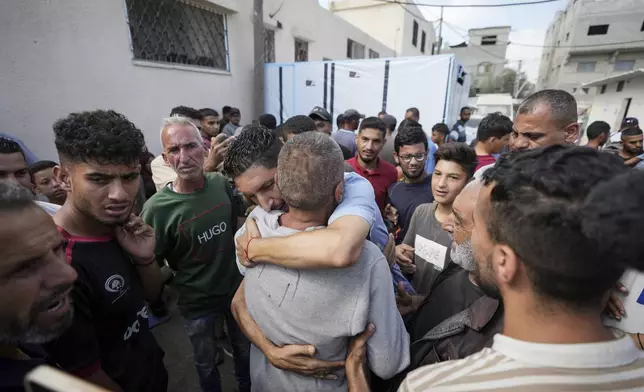 A Palestinian man, back to the camera, who was arrested in the Gaza Strip by the Israeli military and released through the Kissufim crossing point is welcomed by relatives at a hospital in Deir al Balah, central Gaza Strip on Monday, July 1, 2024. (AP Photo/Abdel Kareem Hana)