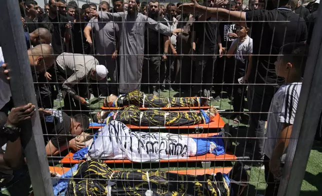 Mourners take the last look at the bodies of four Palestinians, wrapped with Islamic Jihad flags, who were killed by an Israeli airstrike late Tuesday, during their funeral in the West Bank refugee camp of Nur Shams, near Tulkarem, Wednesday, July 3, 2024. Palestinian health officials say four Palestinians were killed by an Israeli airstrike in a refugee camp in the northern West Bank late Tuesday. Israel's military said an aircraft struck a group of militants who were planting explosives in Nur Shams refugee camp near Tulkarem. (AP Photo/Nasser Nasser)