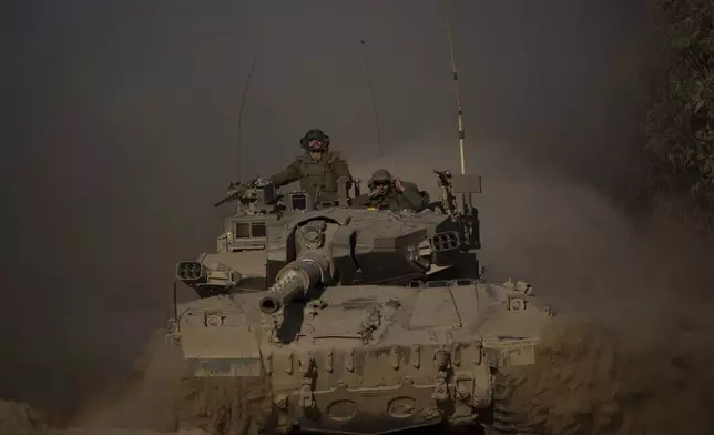 Israeli soldiers move on the top of a tank near the Israeli-Gaza border, as seen from southern Israel, Monday, July 8, 2024. Israeli forces advanced deeper into the Gaza Strip's largest city in pursuit of militants who had regrouped there, sending thousands of Palestinians fleeing on Monday from an area ravaged in the early weeks of the nine-month-long war. (AP Photo/Leo Correa)