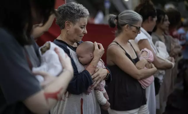 Relatives and supporters of Israeli hostages held by Hamas in the Gaza Strip hold baby dolls during a performance marking nine months since the start of the war and calling for their return, in Tel Aviv, Israel, Sunday, July 7, 2024. (AP Photo/Leo Correa)