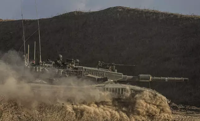 An Israeli soldier moves on the top of a tank near the Israeli-Gaza border, as seen from southern Israel, Sunday, July 14, 2024. (AP Photo/Tsafrir Abayov)