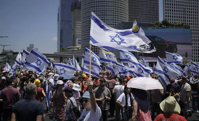 Demonstrators wave Israeli flags during a protest marking nine months since the start of the war and calling for the release of hostages held in the Gaza Strip by the Hamas militant group, in Tel Aviv, Israel, Sunday, July 7, 2024. (AP Photo/Leo Correa)