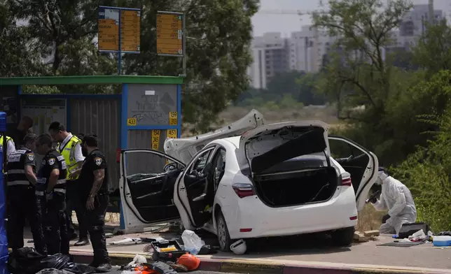 Israeli security forces examine the scene of a suspected ramming attack near Ramla, Israel Sunday, July 14, 2024. According to the authorities a car slammed into pedestrians waiting at a bus stop, leaving at least four injured people. The suspect of the attack was shot and killed while still in his car. (AP Photo/Ohad Zwigenberg)