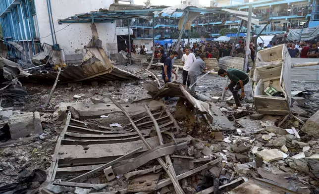 Palestinians look at the aftermath of the Israeli airstrike on a U.N.-run school that killed dozens of people in the Nusseirat refugee camp in the Gaza Strip, Saturday, July 6, 2024. (AP Photo/Saher Alghorra)