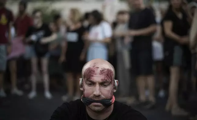 A man painted in red to symbolize blood during a protest marking nine months since the start of the war and calling for the release of hostages held in the Gaza Strip by the Hamas militant group, in Tel Aviv, Israel, Sunday, July 7, 2024. (AP Photo/Leo Correa)