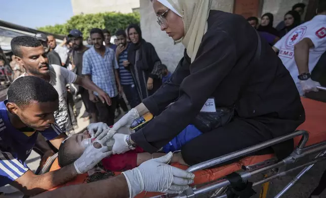 A Palestinian medic helps a child wounded in the Israeli bombardment of the Gaza Strip in a hospital in Deir Al-Balah, Saturday, July 27, 2024. (AP Photo/Abdel Kareem Hana)