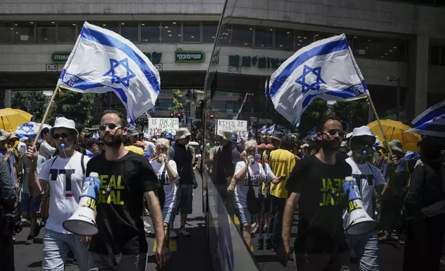 Demonstrators march with Israeli flags during a protest marking nine months since the start of the war and calling for the release of hostages held in the Gaza Strip by the Hamas militant group, in Tel Aviv, Israel, Sunday, July 7, 2024. (AP Photo/Leo Correa)