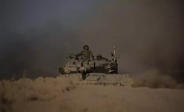 Israeli soldiers move on the top of a tank near the Israeli-Gaza border, as seen from southern Israel, Monday, July 8, 2024. Israeli forces advanced deeper into the Gaza Strip's largest city in pursuit of militants who had regrouped there, sending thousands of Palestinians fleeing on Monday from an area ravaged in the early weeks of the nine-month-long war. (AP Photo/Leo Correa)