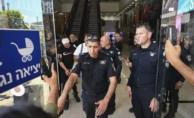 Israeli police arrest a man outside a shopping mall following a stabbing attack in Karmiel, northern Israel, Wednesday, July 3, 2024. One person was killed and one person wounded in a stabbing attack at a shopping mall in what Israeli police say was a terrorist attack. The police say the assailant was killed. They did not provide the name or nationality of the attacker. (AP Photo/Rami Shlush)