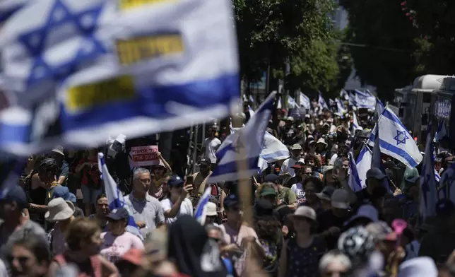 Demonstrators march with Israeli flags during a protest marking nine months since the start of the war and calling for the release of hostages held in the Gaza Strip by the Hamas militant group, in Tel Aviv, Israel, Sunday, July 7, 2024. (AP Photo/Leo Correa)