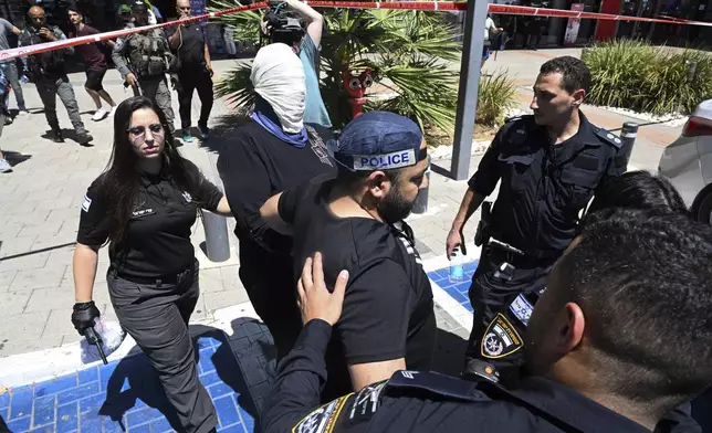 Israeli police arrest a woman outside a shopping mall following a stabbing attack in Karmiel, northern Israel, Wednesday, July 3, 2024. One person was killed and one person wounded in a stabbing attack at a shopping mall in what Israeli police say was a terrorist attack. The police say the assailant was killed. They did not provide the name or nationality of the attacker. (AP Photo/Rami Shlush)
