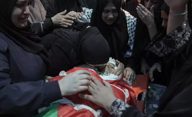 Relatives of Muhammad Sarhan,15, mourn around his body, draped in the Palestinian flag, during his funeral in the West Bank town of Tulkarem, Tuesday, July 2, 2024. Palestinian health officials say Sarhan and another woman were shot and killed, and four people were wounded by Israeli forces during a raid in the northern West Bank on Monday. (AP Photo/Majdi Mohammed)