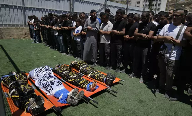Mourners pray over the bodies of four Palestinians, wrapped with Islamic Jihad flags, who were killed by an Israeli airstrike late Tuesday, during their funeral in the West Bank refugee camp of Nur Shams, near Tulkarem, Wednesday, July 3, 2024. Palestinian health officials say four Palestinians were killed by an Israeli airstrike in a refugee camp in the northern West Bank late Tuesday. Israel's military said an aircraft struck a group of militants who were planting explosives in Nur Shams refugee camp near Tulkarem. (AP Photo/Nasser Nasser)