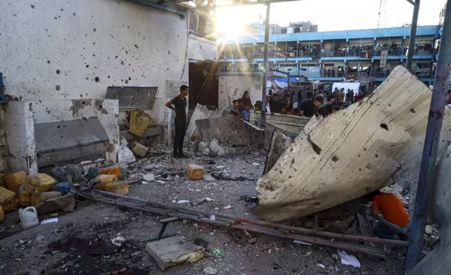 Palestinians look at the aftermath of the Israeli airstrike on a U.N.-run school that killed dozens of people in the Nusseirat refugee camp in the Gaza Strip, Saturday, July 6, 2024. (AP Photo/Saher Alghorra)