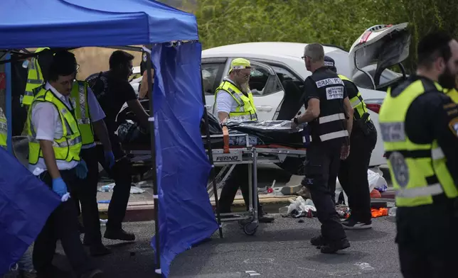 Israeli police officers work at the scene of a suspected ramming attack near Ramla, Israel, Sunday, July 14, 2024. According to the authorities a car slammed into pedestrians waiting at a bus stop, leaving at least four injured people. The suspect of the attack was shot and killed while still in his car. (AP Photo/Ohad Zwigenberg)