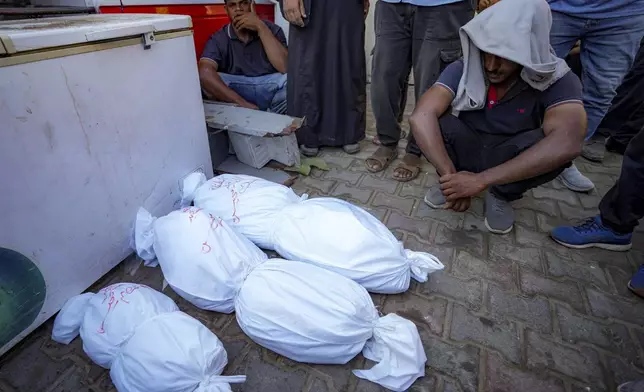 Palestinians sit around the bodies of their relatives killed in the Israeli bombardment of the Gaza Strip, at a hospital in Deir al-Balah, Thursday, July 18, 2024. (AP Photo/Abdel Kareem Hana)