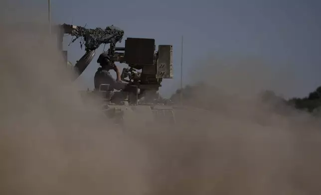 An Israeli soldier moves on an armoured personnel carriers (APC) near the Israeli-Gaza border, as seen from southern Israel, Monday, July 8, 2024. Israeli forces advanced deeper into the Gaza Strip's largest city in pursuit of militants who had regrouped there, sending thousands of Palestinians fleeing on Monday from an area ravaged in the early weeks of the nine-month-long war. (AP Photo/Leo Correa)