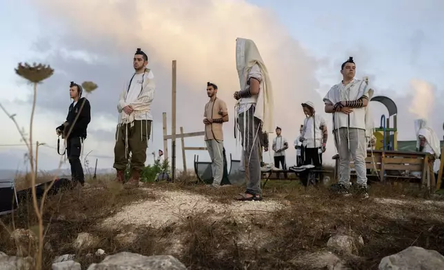 Jewish settlers pray in the Eviatar outpost in the Israeli-occupied West Bank during morning prayers calling for the legalization of the outpost and the return of the hostages held in the Gaza Strip by the Hamas militant group, Sunday, July 7, 2024. Far-right ministers in Israel’s government have said they want to legalize unauthorized outposts in the West Bank in a sweeping expansion of settlements. (AP Photo/Ohad Zwigenberg)