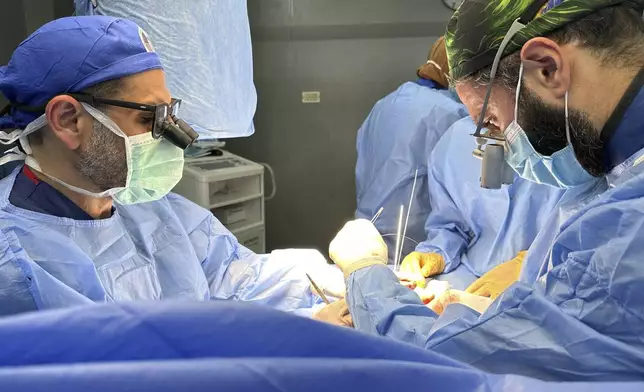 This handout photo taken on May 12, 2023 shows Dr. Adam Hamawy, left, a former U.S. Army combat plastic surgeon who volunteered in Gaza in May and Dr. Mohammed Tahir, a British surgeon, performing surgery on mangled hand from a blast injury at the European General Hospital, in Khan Younis, Gaza. (Adam Hamawy via AP)