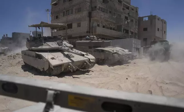 Israeli tanks are seen next to destroyed buildings in the southern Gaza Strip, Wednesday, July 3, 2024. The Israeli military invited reporters for a tour of Rafah, where the military has been operating since May 6. (AP Photo/Ohad Zwigenberg, Pool)