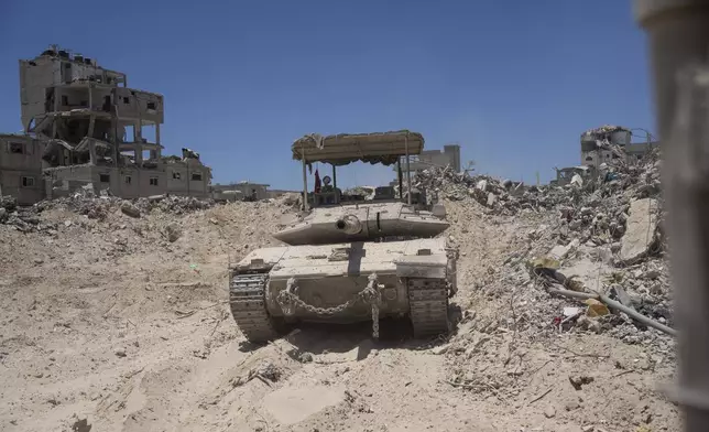 An Israeli tank is seen next to destroyed buildings in the southern Gaza Strip, Wednesday, July 3, 2024. The Israeli military invited reporters for a tour of Rafah, where the military has been operating since May 6. (AP Photo/Ohad Zwigenberg, Pool)